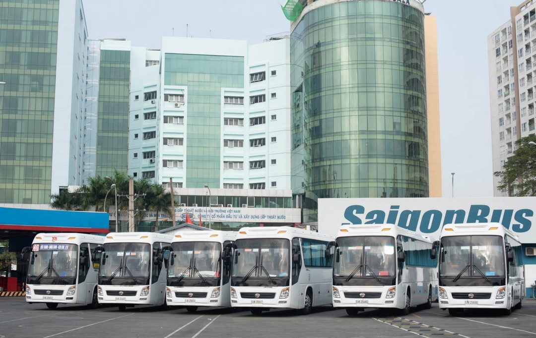 A fleet of white regional coaches lined up at a Saigon bus terminal — reliable transport option for travellers heading to Cai Be