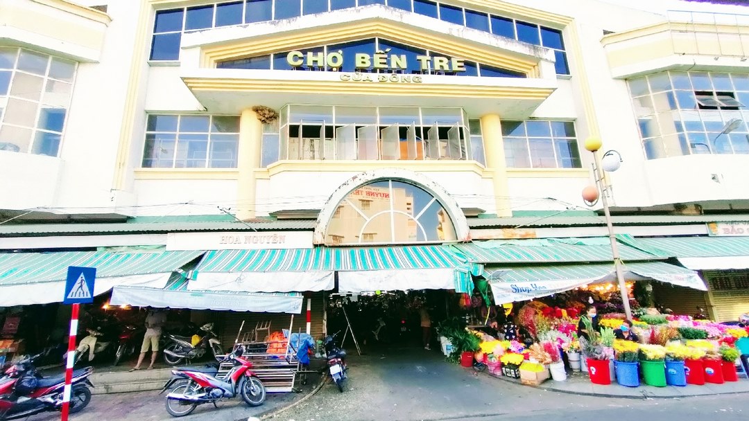 Ben Tre Market - busy entrances and colorful flower stalls spilling onto the sidewalk