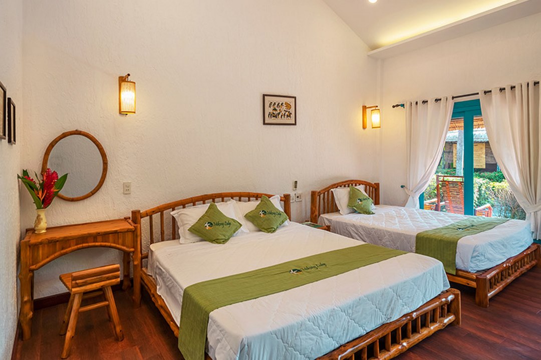 Bright and airy bungalow interior with twin beds and wooden furnishings - blending comfort and rustic charm at Mekong Lodge