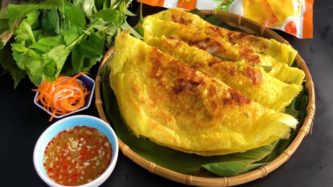 Crispy bánh xèo with fresh herbs, pickles, and a tangy dipping sauce