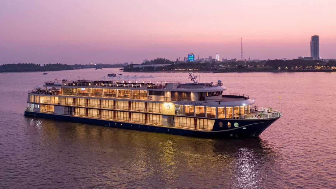 Victoria Mekong cruise gliding at dusk—warm lights reflecting on the river