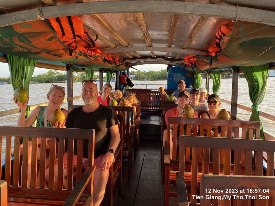 Group of travelers smiling together on a boat ride through the Delta’s palm-lined canals — a highlight of organized tours
