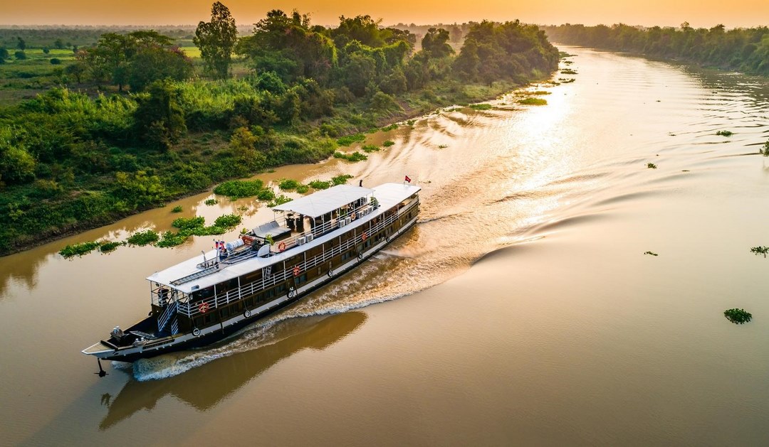 Mekong river cruise sailing through quiet waterways at golden hour