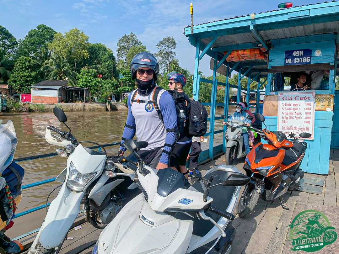 Motorbikes board a small ferry in the Mekong Delta, showcasing part of the adventure and transitions required on rural routes