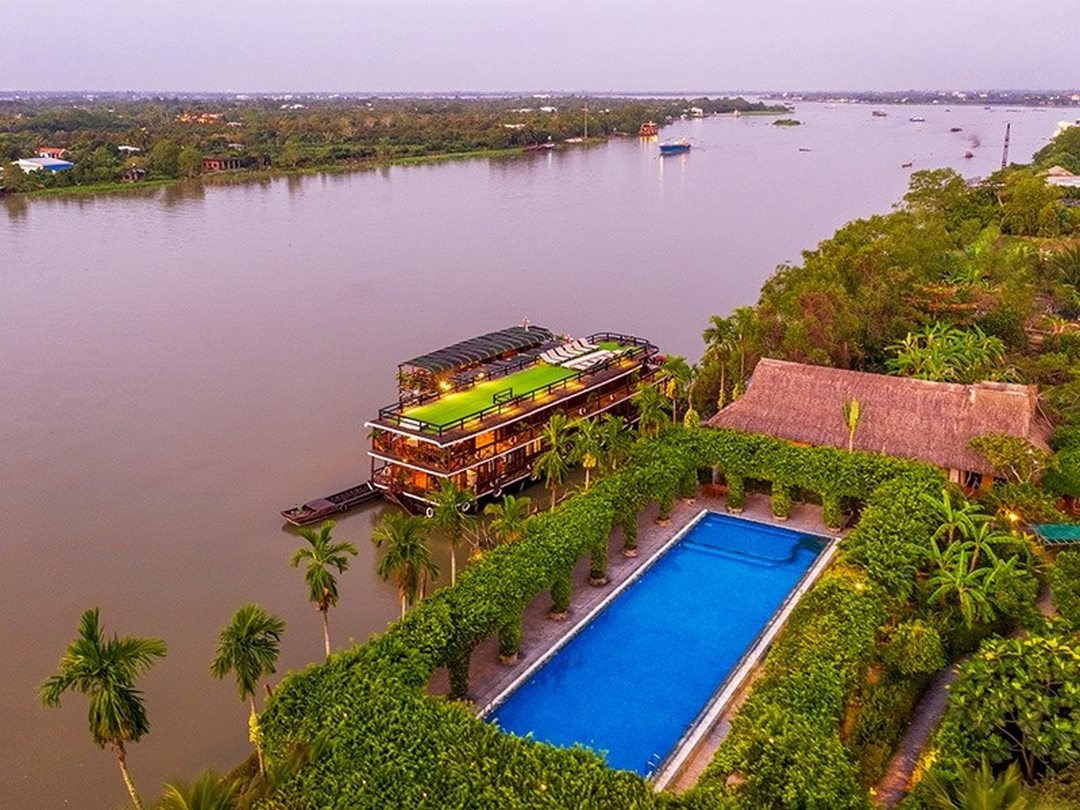Sunset view over the river from Mekong Lodge, with pool and lodge buildings overlooking the water