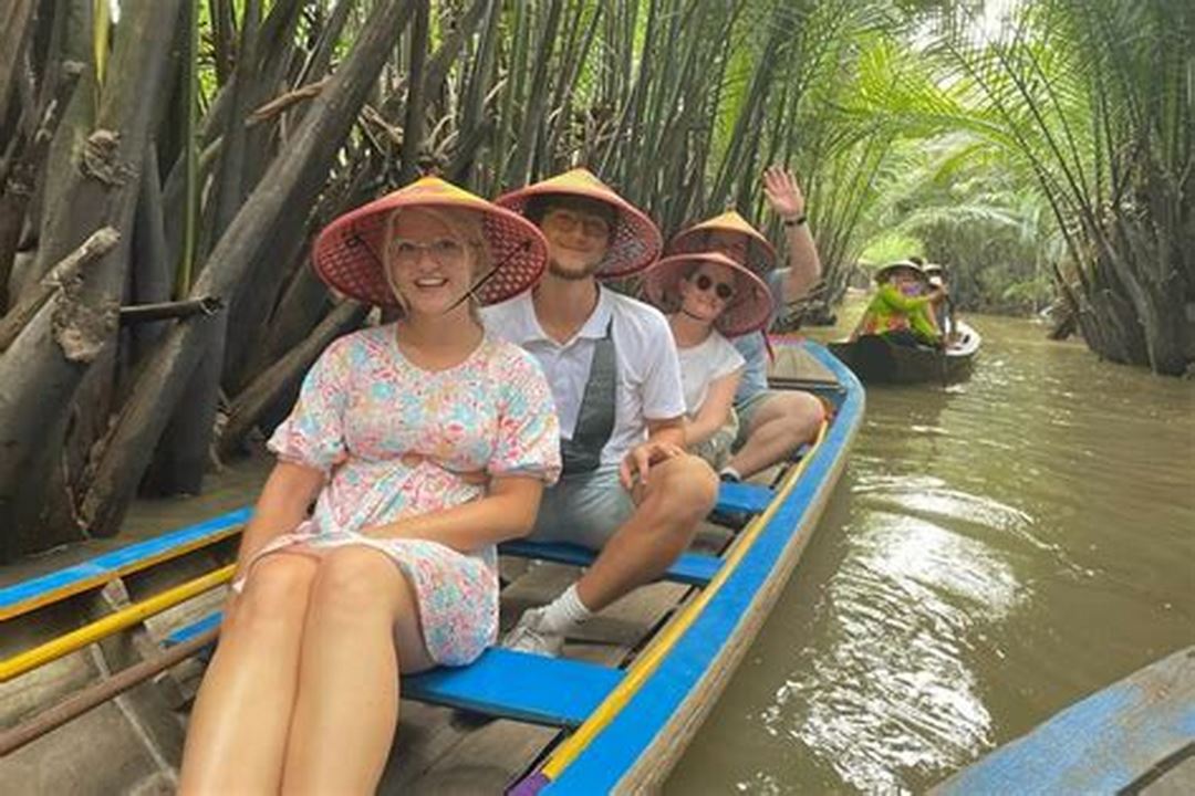 A private boat weaving through narrow canals lined with lush greenery — offering an intimate, serene transfer experience from Ho Chi Minh to Can Tho