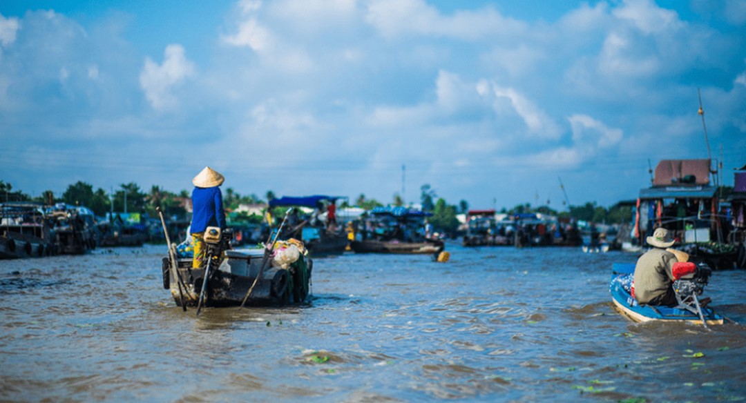 A small tour boat gliding through the waterways, passing floating markets and riverside houses – a signature experience on the journey from Ho Chi Minh City to Can Tho