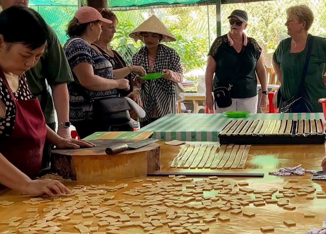 Coconut candy workshop in Ben Tre workers stirring sweet coconut mixture over fire