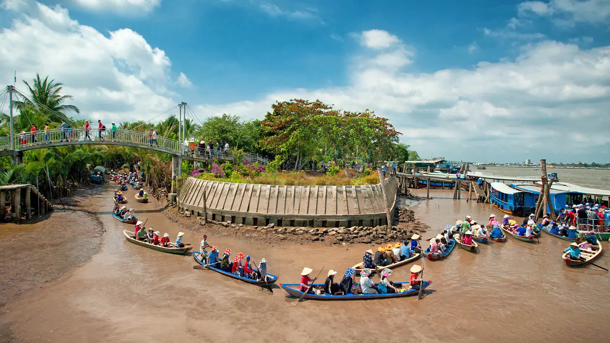 Floating boats in Thoi Son Islet canals, surrounded by water palms, under a bright sky